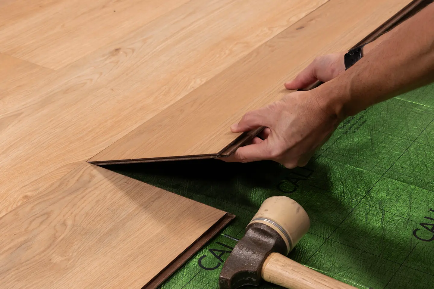 Harbor Honey laminate flooring with precision T-molding transition — professional laminate installation detail in Orlando